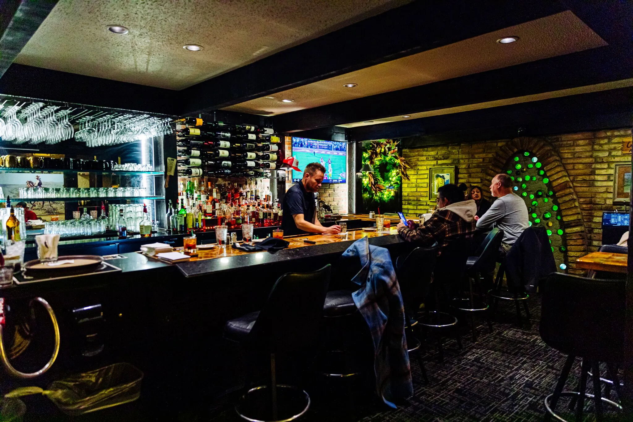 The bar at The Drover offers full service, plus small tables for parties waiting for a table. The bottles embedded in the west wall of the bar are a detail left over from the Cork ’n Cleaver, which was the chain restaurant in the building before The Drover opened in 1977.