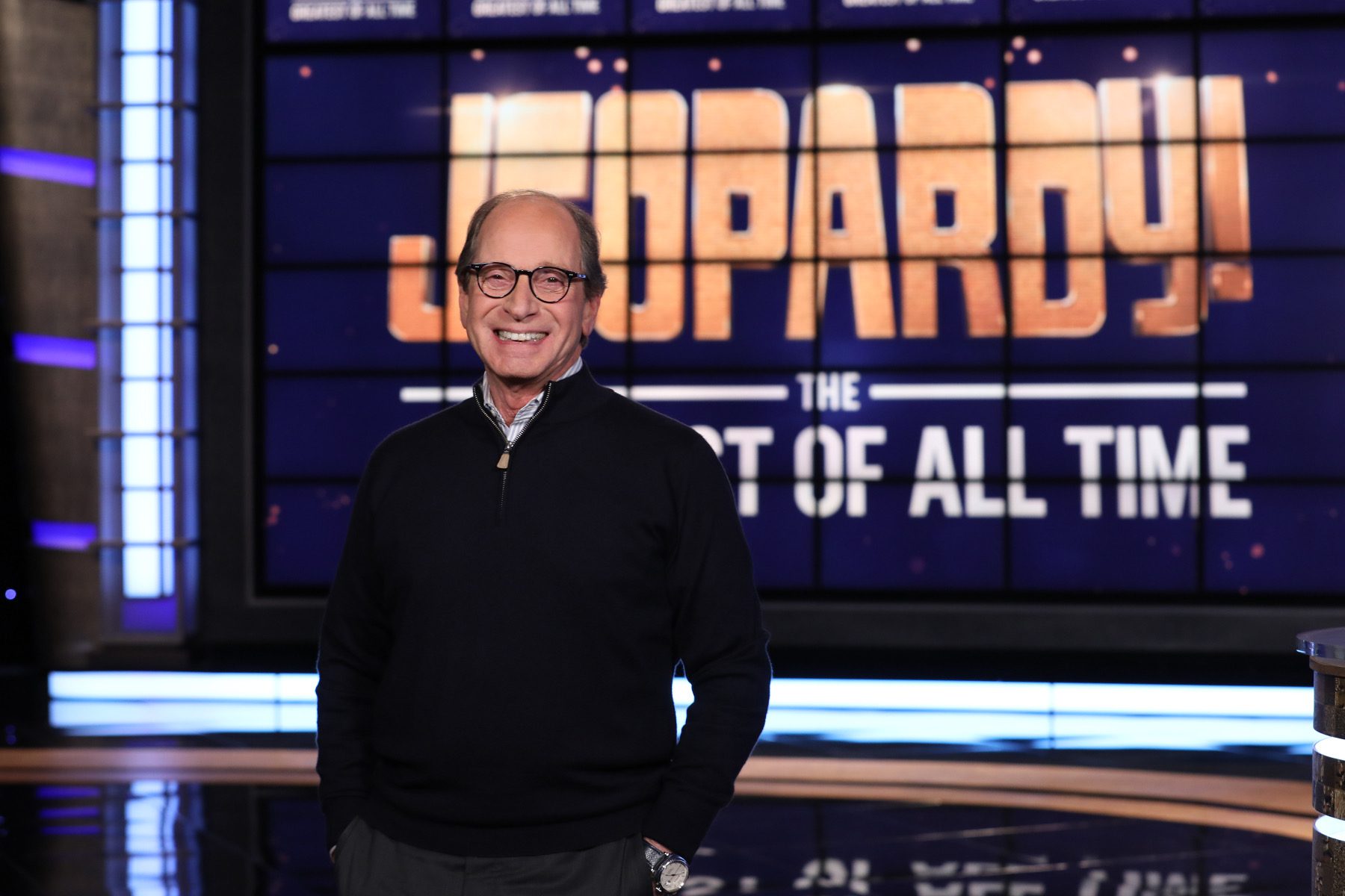 Harry Friedman, standing in front of a Jeopardy! sign
