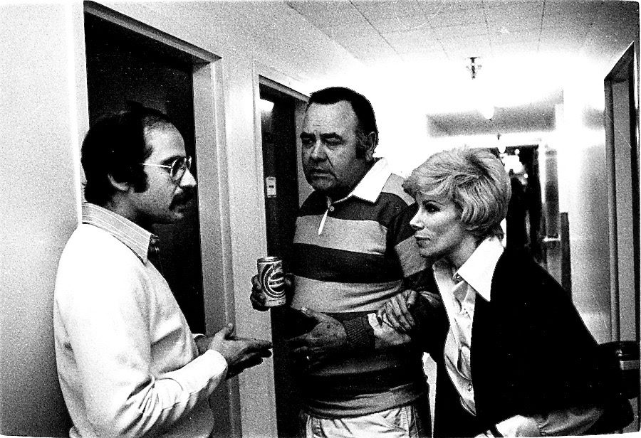 Harry Friedman, left, talks in a hallway with comedians Jonathan Winters and Joan Rivers.