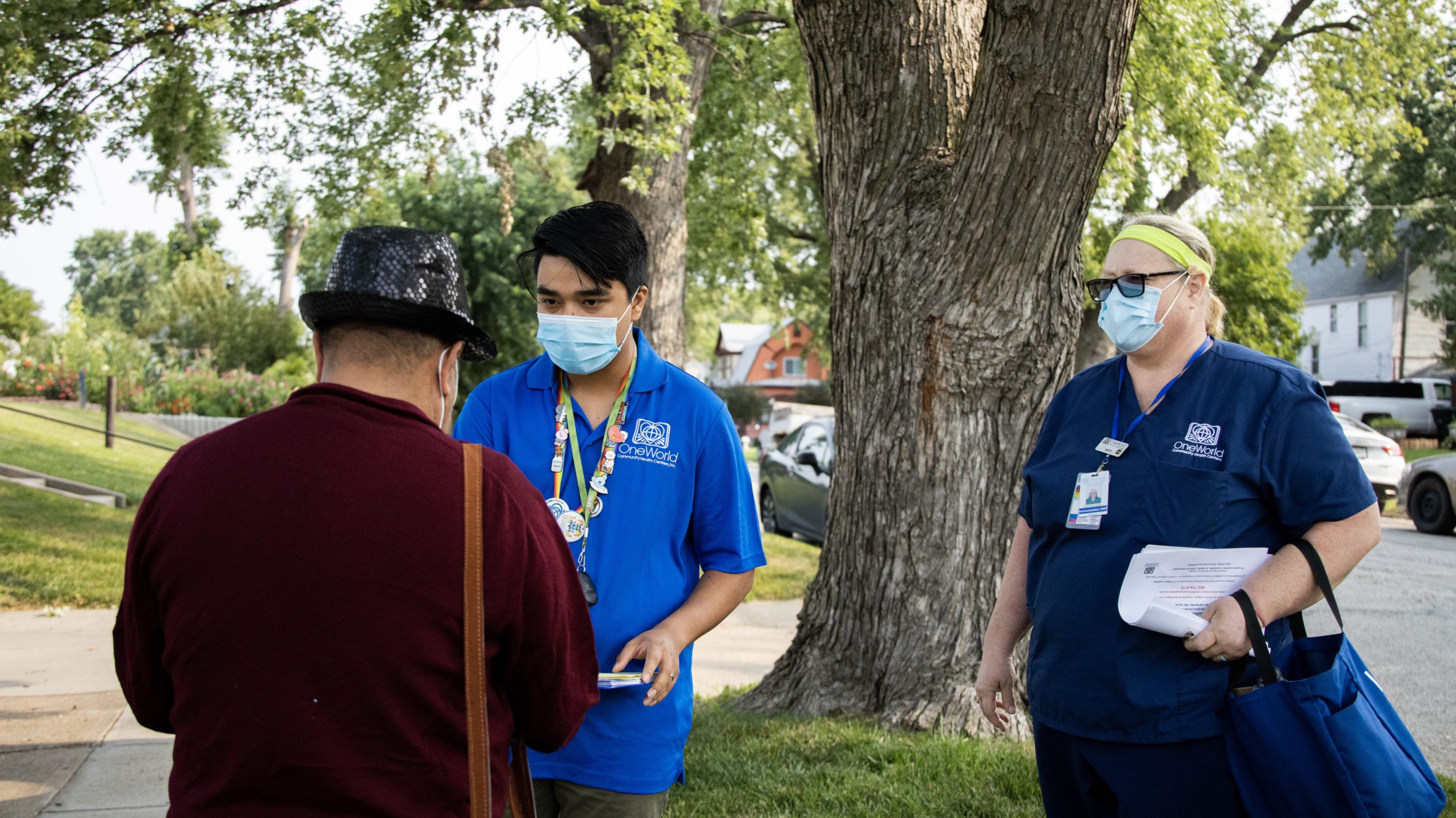 Eddie Nunez and Mary McConnaughey, employees of One World Community Health Centers, talk to a passerby as they go door-to-door in a South Omaha neighborhood, offering residents the COVID-19 vaccine.