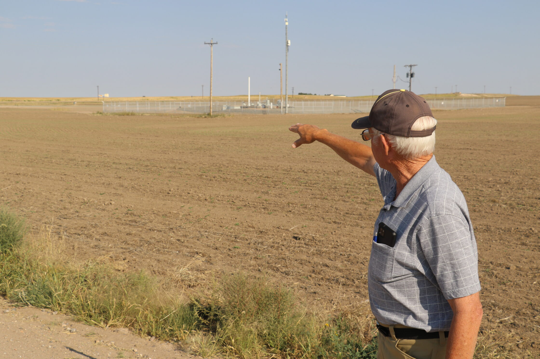 Farmer Jim Young gestures to a missile silo on his land near Harrisburg in Banner County. Young and other landowners are frustrated by the Air Force’s decision to ban windmills within two nautical miles of these missile silos – a decision that has paused and may end the biggest wind energy project in Nebraska history. Photo by Fletcher Halfaker for the Flatwater Free Press