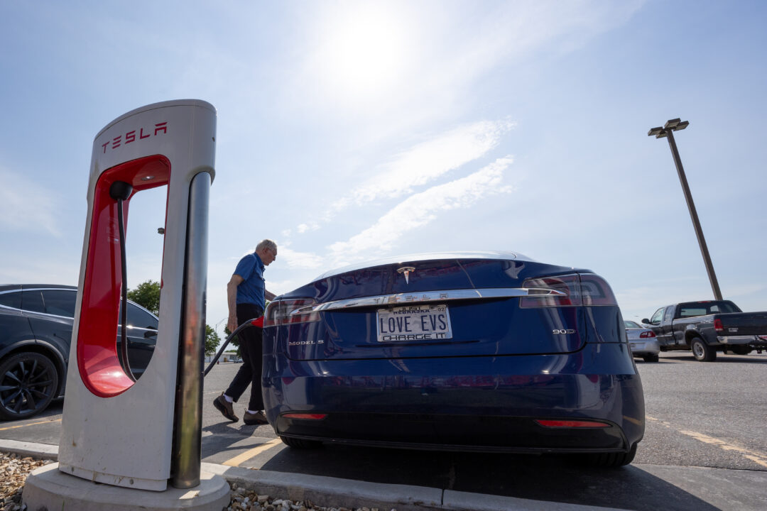 Don Cox charges a Tesla Model S at a Tesla Supercharger station at a Runza parking lot in Lincoln on July 16, 2024. In the early days of owning an EV in Nebraska, before there were reliable public chargers, Cox said he sometimes had to charge at an RV park. Photo by Naomi Delkamiller/Flatwater Free Press